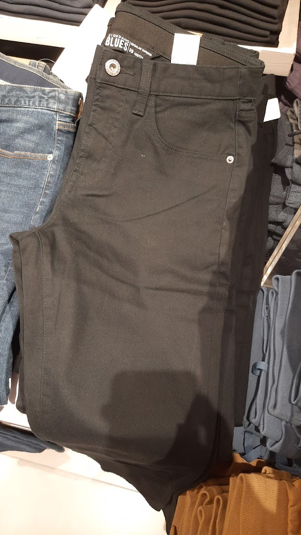Close-up of folded black Giordano Blues regular tapered trousers on a retail display.