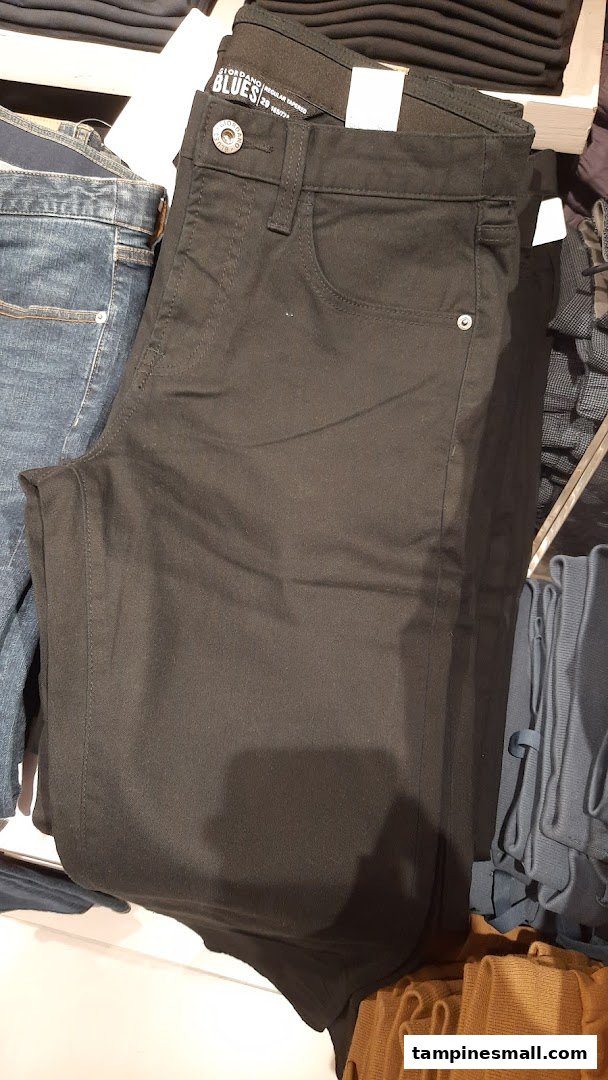 Close-up of folded black Giordano Blues regular tapered trousers on a retail display.