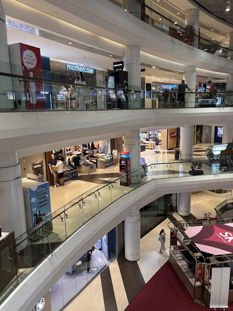 A multi-level view of a vibrant shopping mall interior with various retail stores and shoppers.