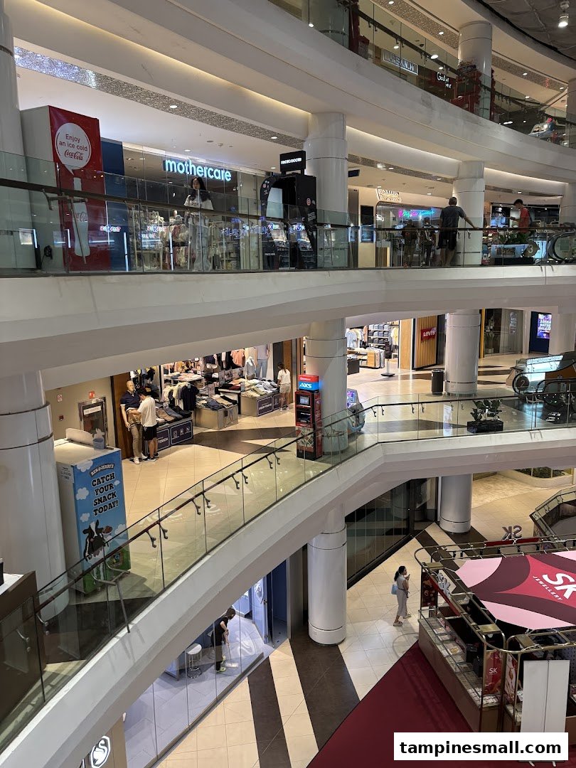 A multi-level view of a vibrant shopping mall interior with various retail stores and shoppers.