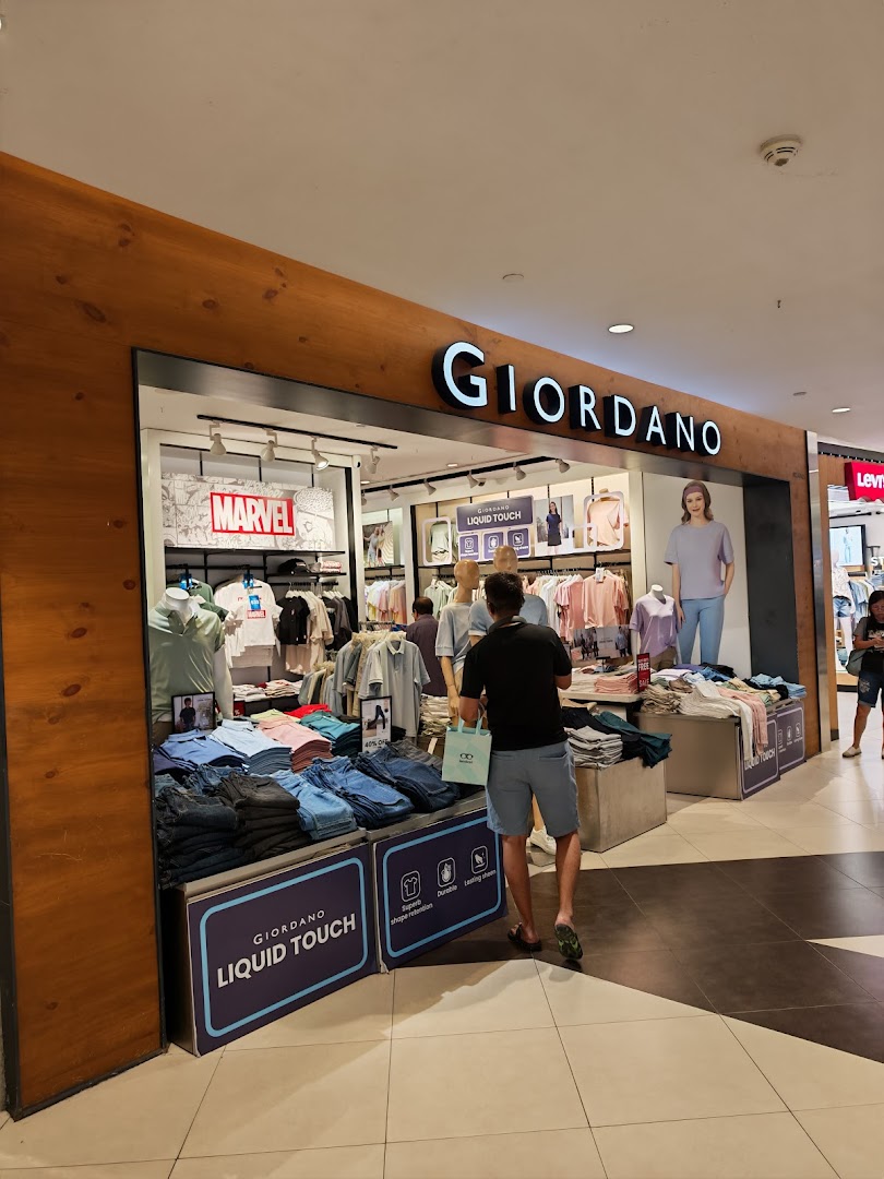 A customer browses clothing at the entrance of a Giordano retail store, showcasing its modern apparel.