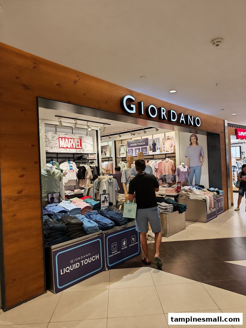 A customer browses clothing at the entrance of a Giordano retail store, showcasing its modern apparel.