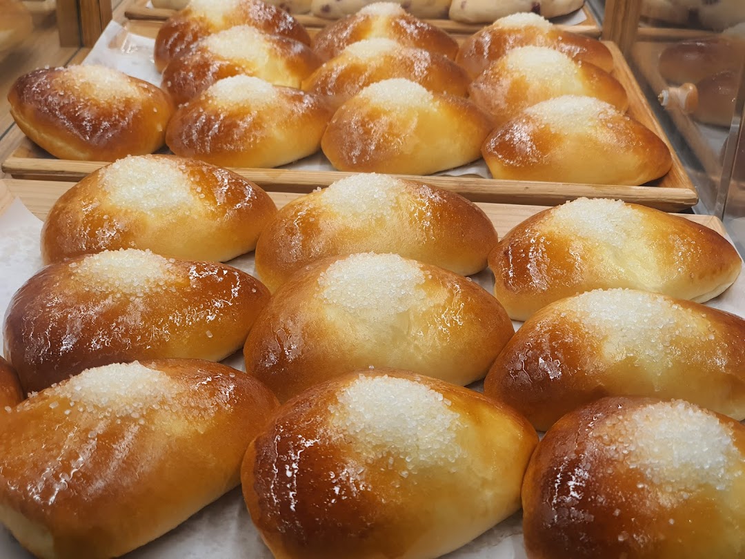 Close-up view of freshly baked, golden-brown buns topped with sparkling sugar crystals on display.