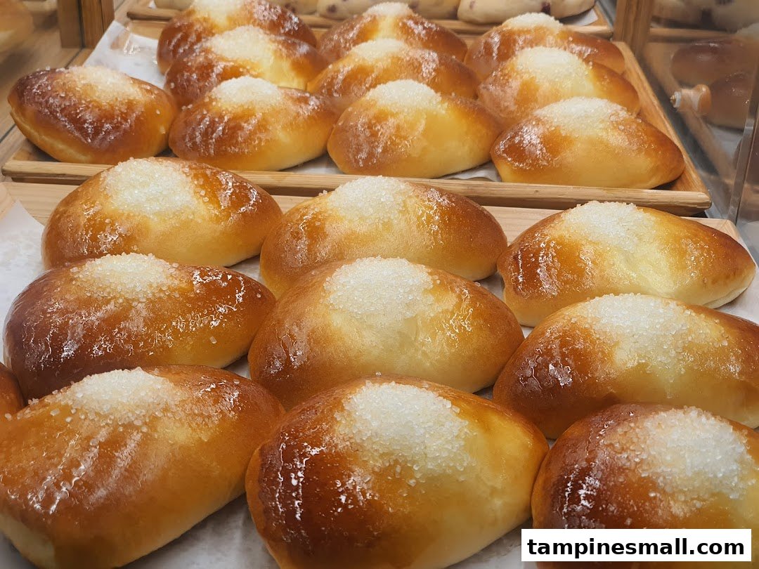 Close-up view of freshly baked, golden-brown buns topped with sparkling sugar crystals on display.