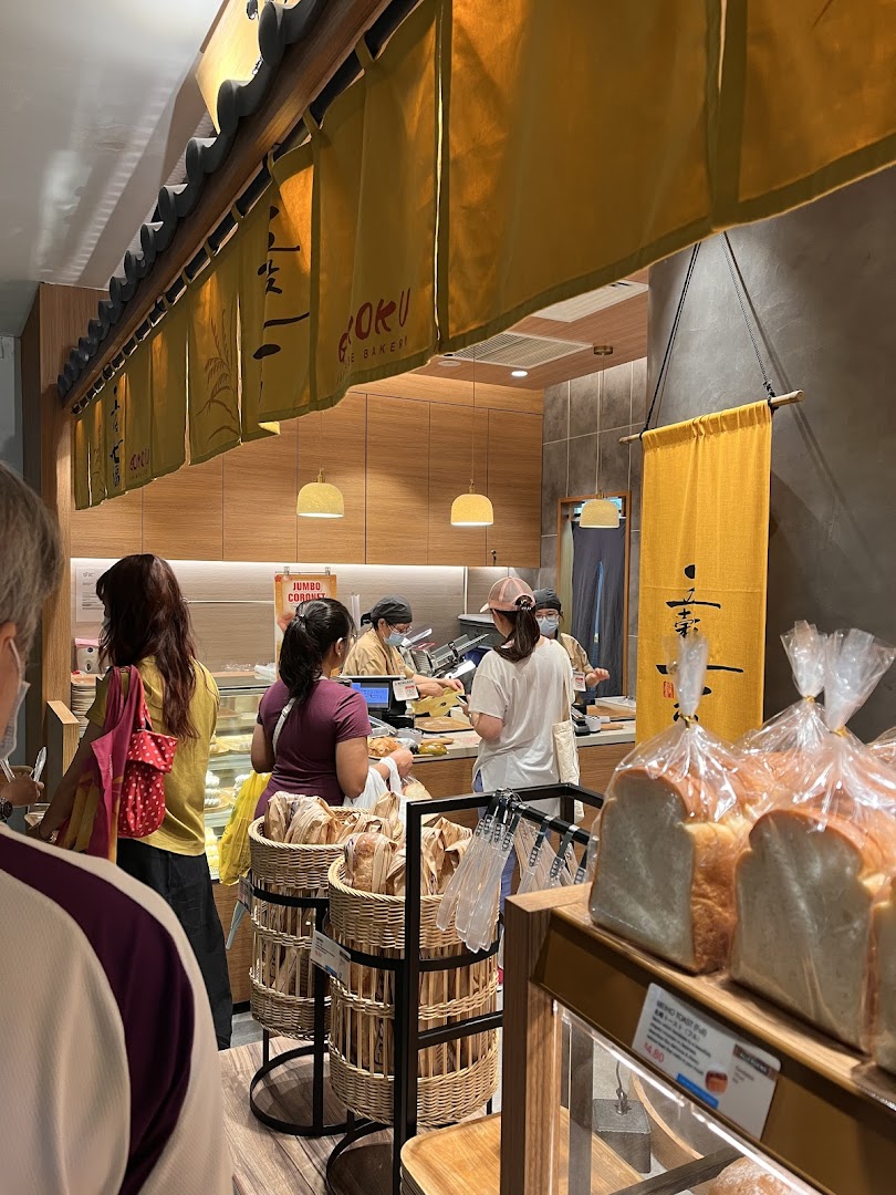 Customers queueing at the counter of a bustling Japanese bakery, with fresh bread on display.