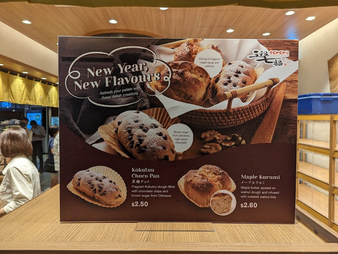 A promotional display board showcasing new bakery items with their descriptions and prices.