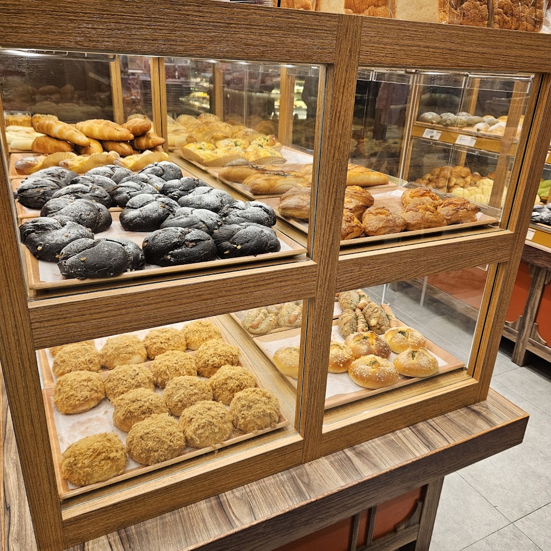 A display case filled with a variety of freshly baked Japanese breads and pastries at Gokoku Japanese Bakery.