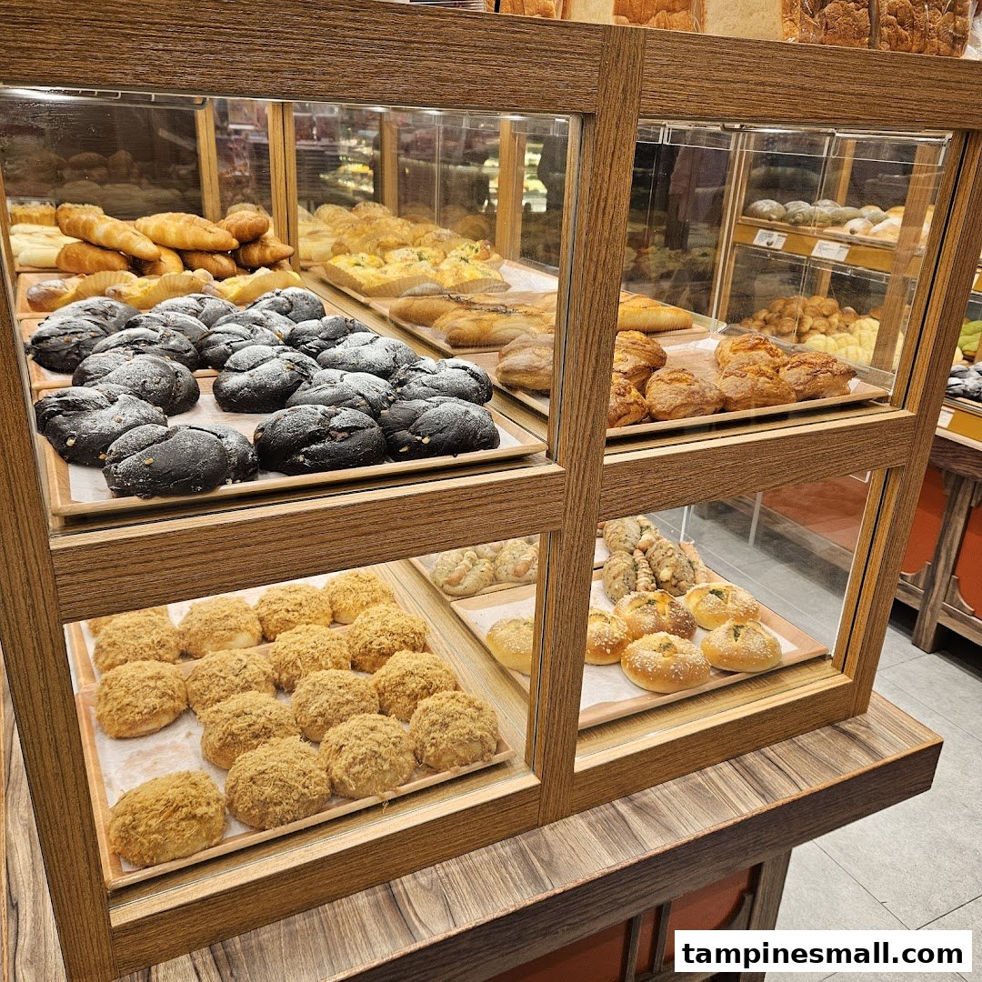 A display case filled with a variety of freshly baked Japanese breads and pastries at Gokoku Japanese Bakery.