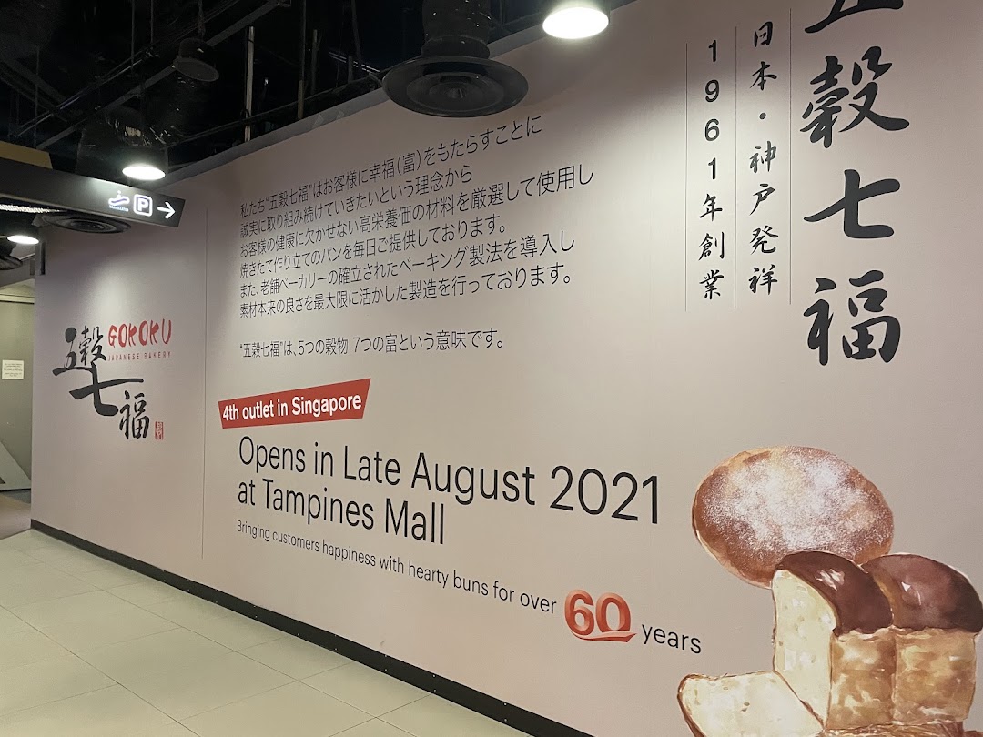 A large wall mural announcing the opening of Gokoku Japanese Bakery at Tampines Mall, featuring brand philosophy and bakery items.