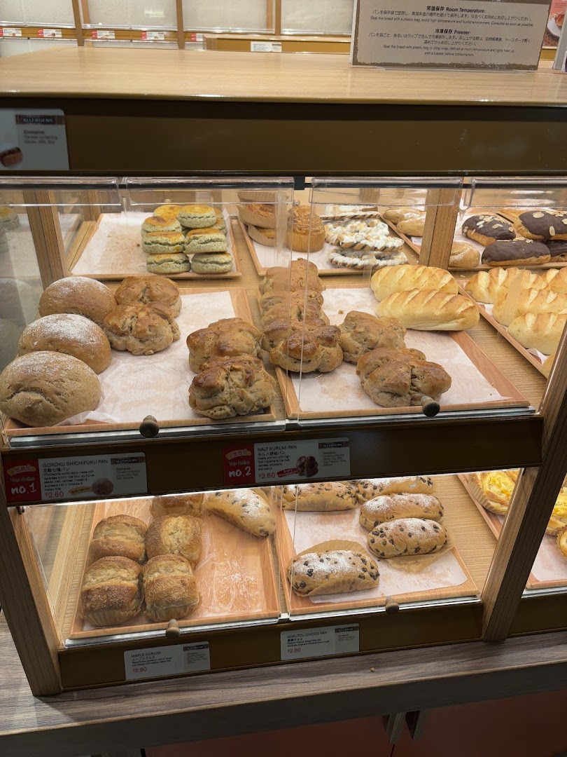 A vibrant display of freshly baked Japanese breads and pastries in a bakery showcase.