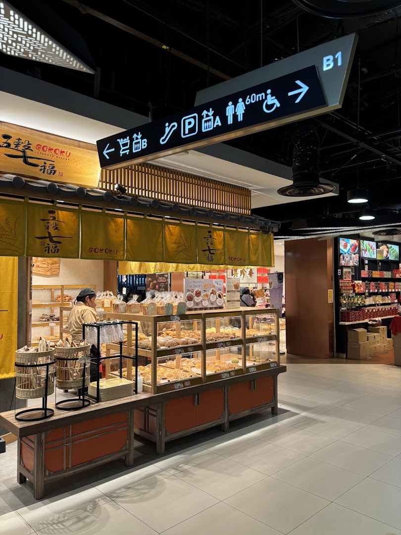 The inviting front of Gokoku Japanese Bakery, showcasing fresh bread displays and a staff member.