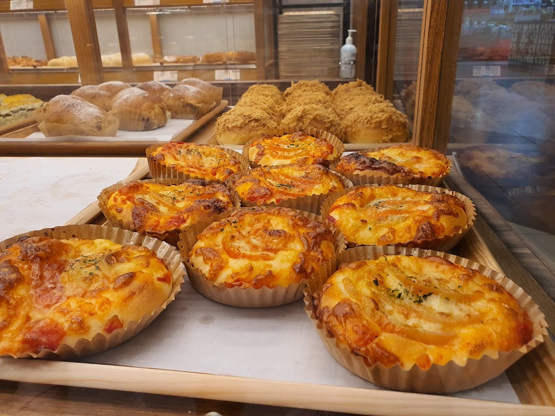 A close-up view of freshly baked savory and sweet buns displayed in a bakery case.