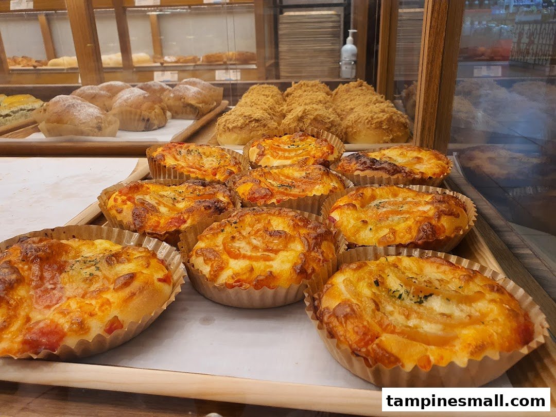 A close-up view of freshly baked savory and sweet buns displayed in a bakery case.