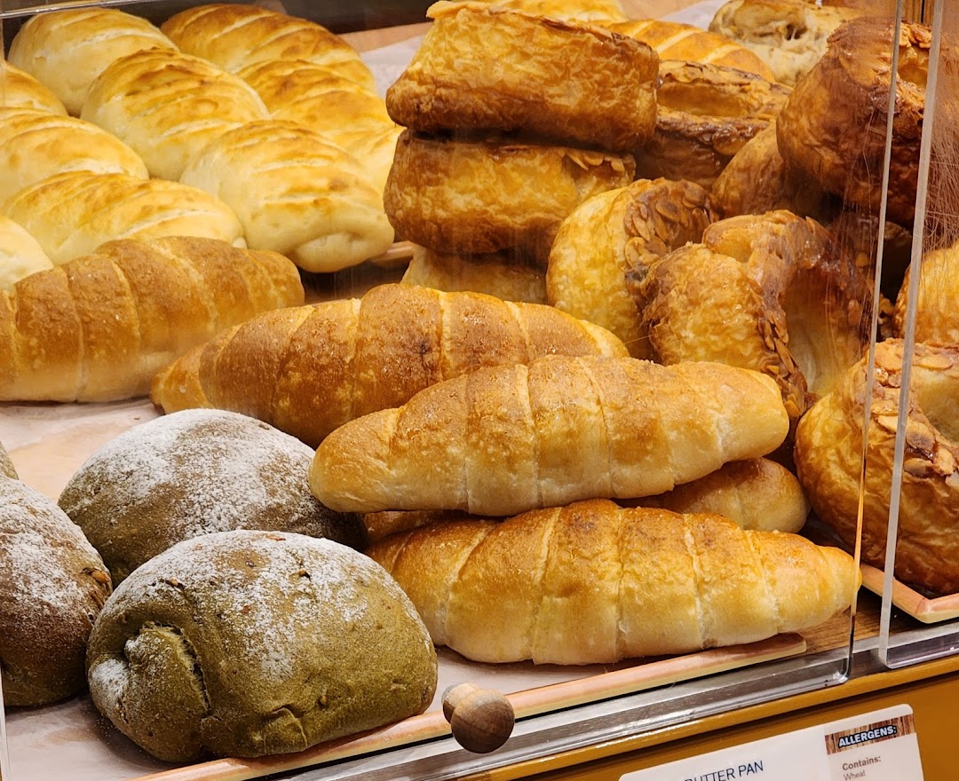 A close-up view of various freshly baked bread and pastries displayed in a bakery showcase.