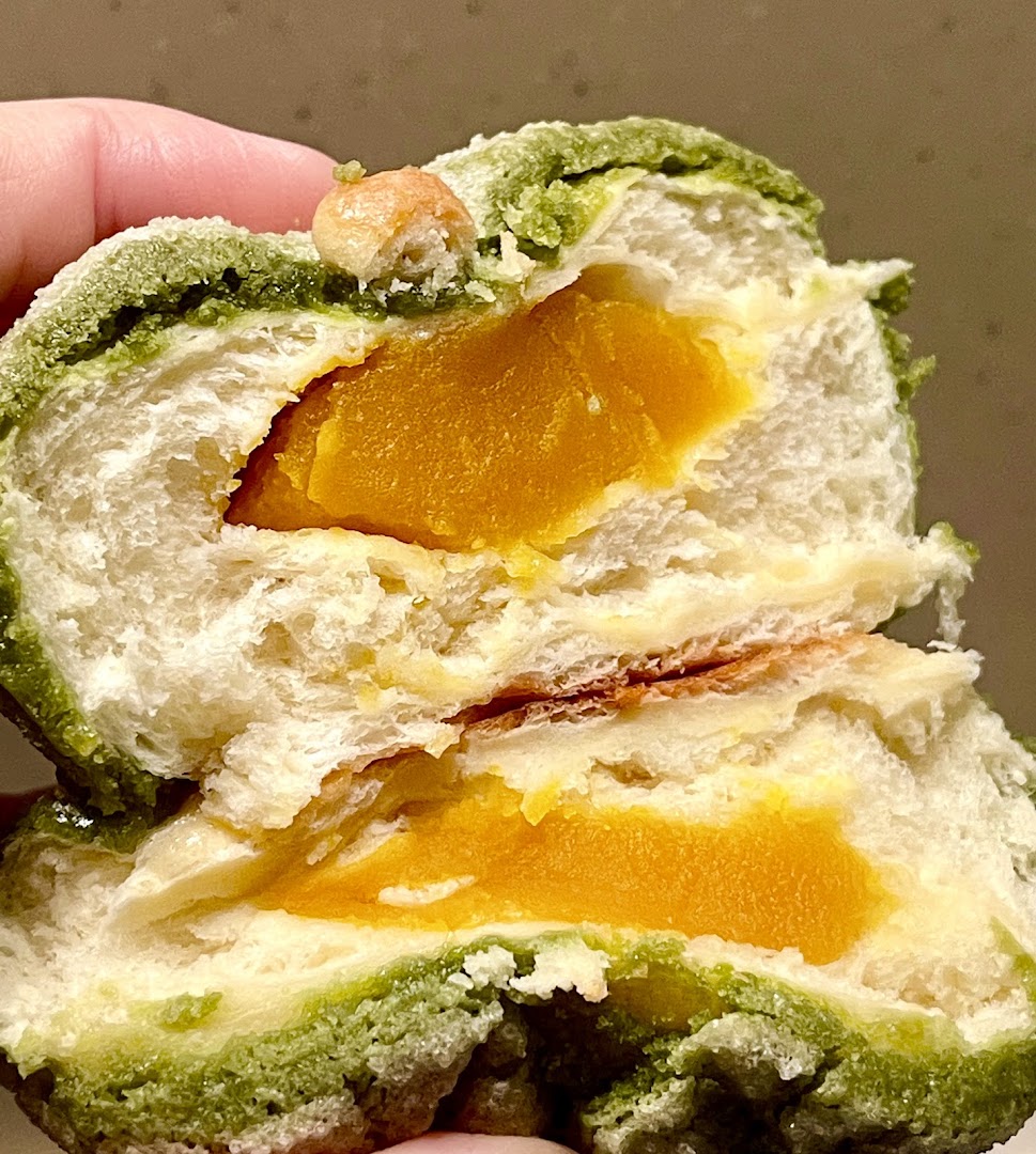 Close-up of a green-dusted bun cut open, revealing a vibrant yellow filling.