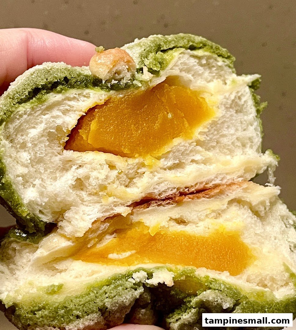 Close-up of a green-dusted bun cut open, revealing a vibrant yellow filling.