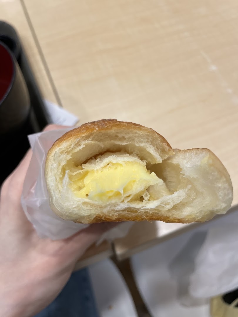 Close-up of a freshly baked pastry from Gokoku Japanese Bakery, revealing its rich, creamy custard filling.