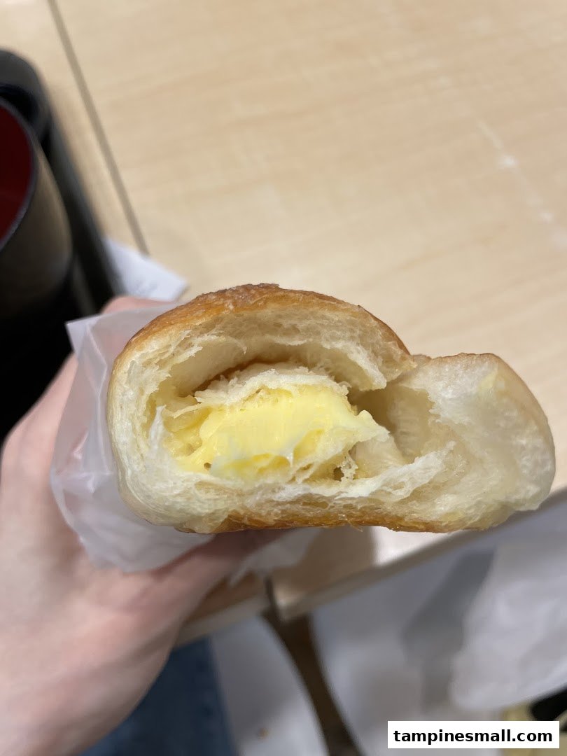 Close-up of a freshly baked pastry from Gokoku Japanese Bakery, revealing its rich, creamy custard filling.