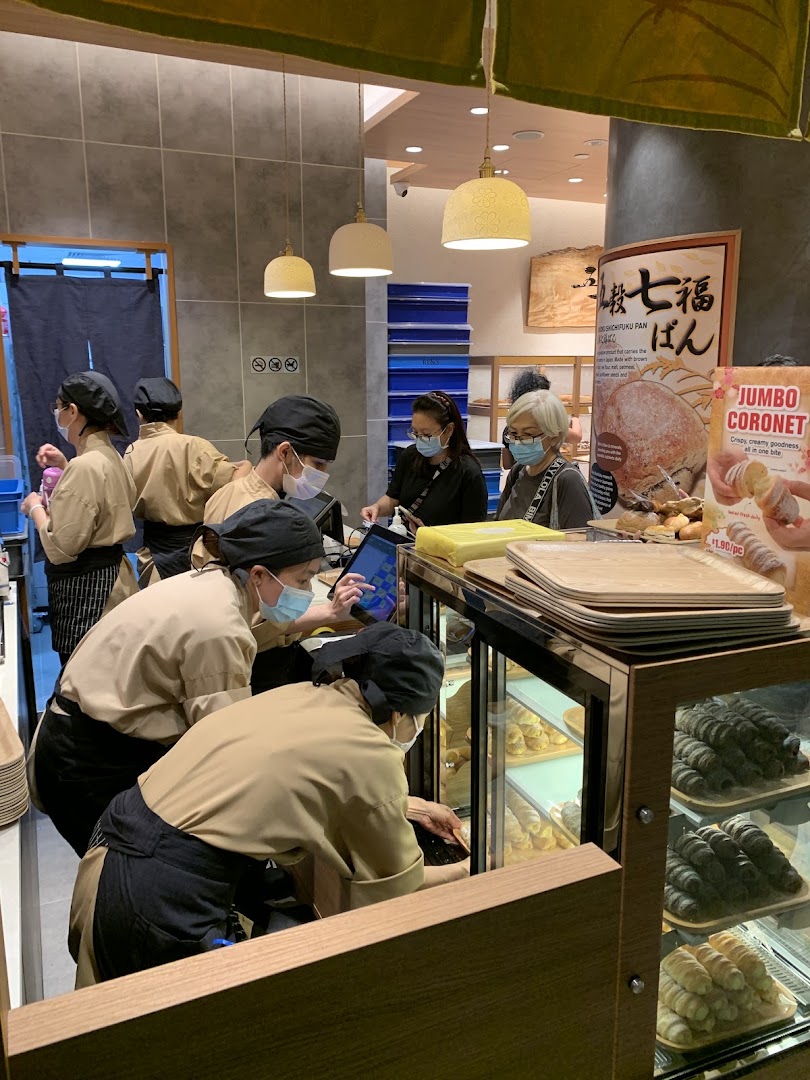 Inside Gokoku Japanese Bakery, staff assist customers amidst displays of freshly baked Japanese breads and pastries.
