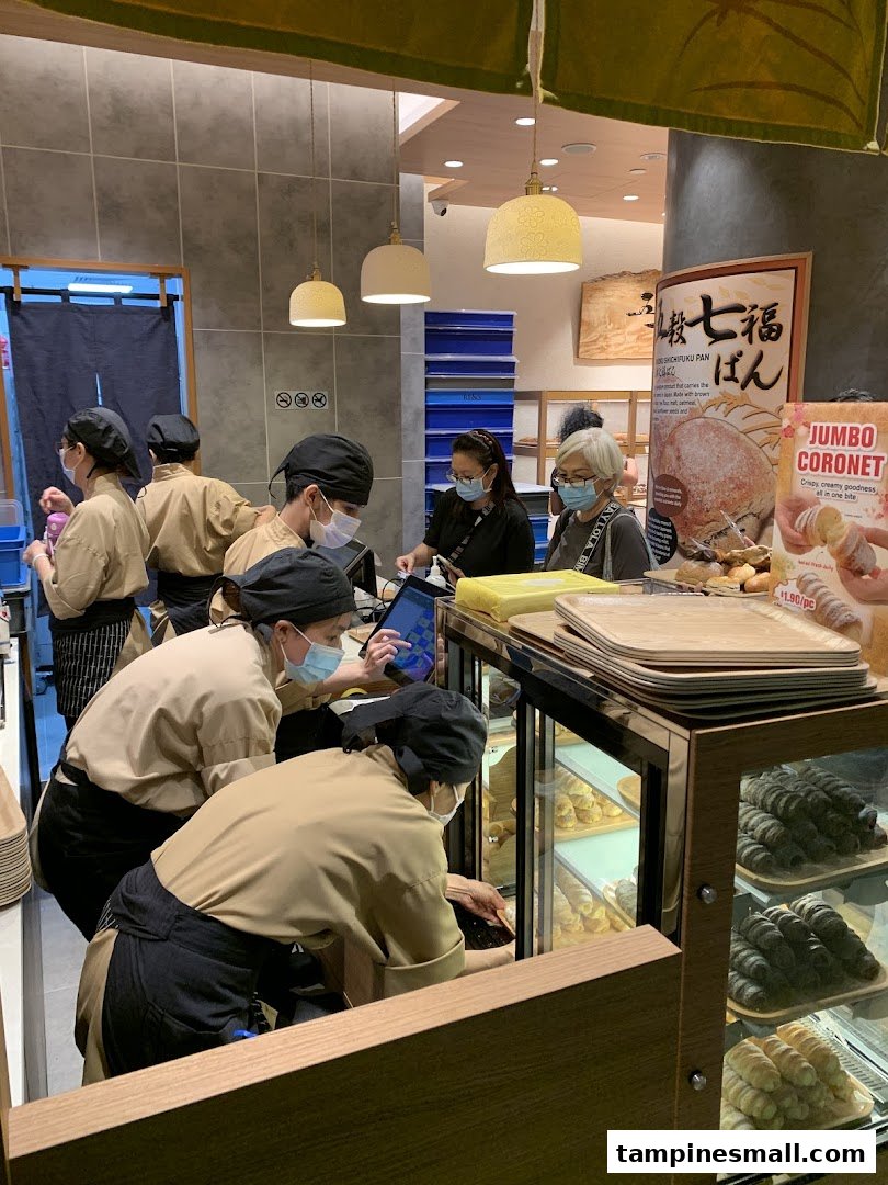 Inside Gokoku Japanese Bakery, staff assist customers amidst displays of freshly baked Japanese breads and pastries.