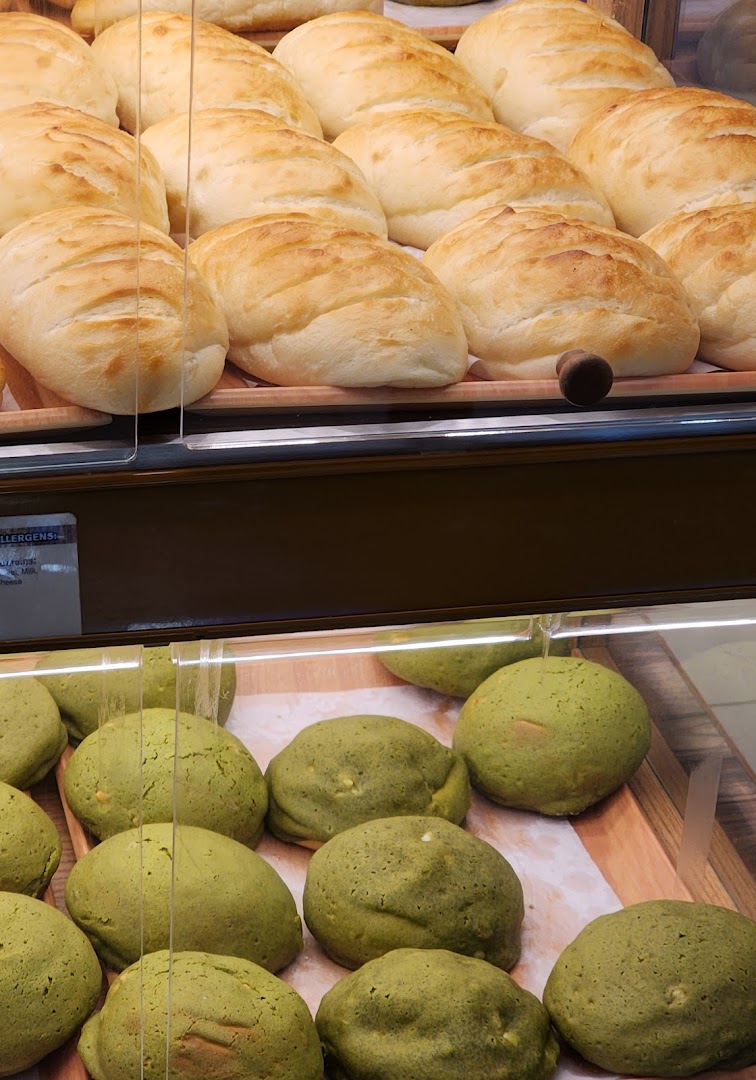 Close-up of freshly baked light-colored and green buns displayed in a bakery case.