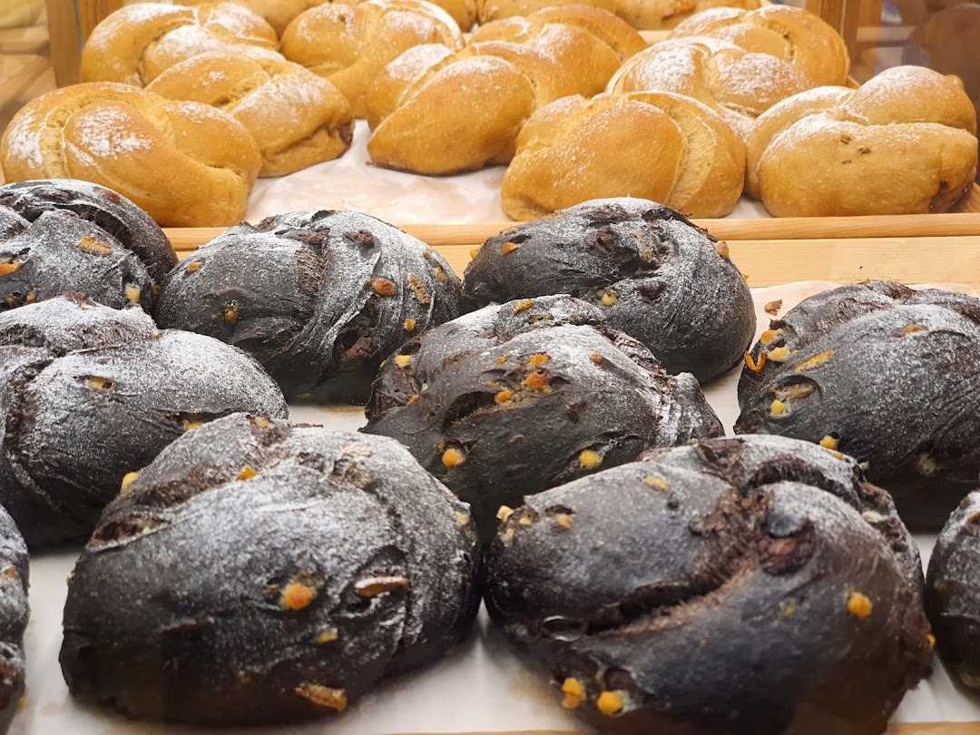 Close-up of freshly baked dark and light bread rolls on display at Gokoku Japanese Bakery.