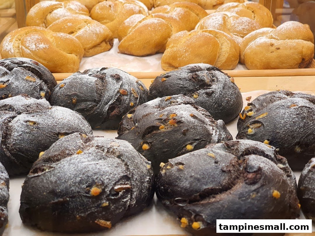 Close-up of freshly baked dark and light bread rolls on display at Gokoku Japanese Bakery.