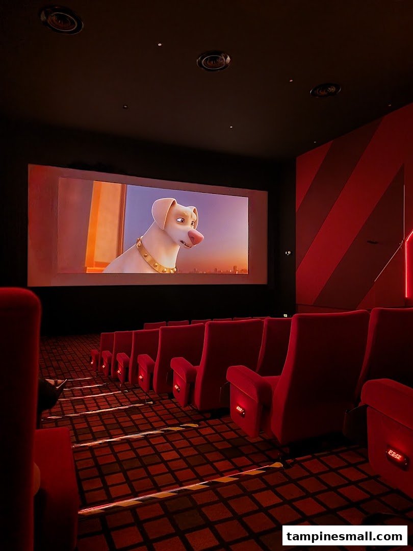 A cinema hall with comfortable red seats and a large screen displaying an animated movie.
