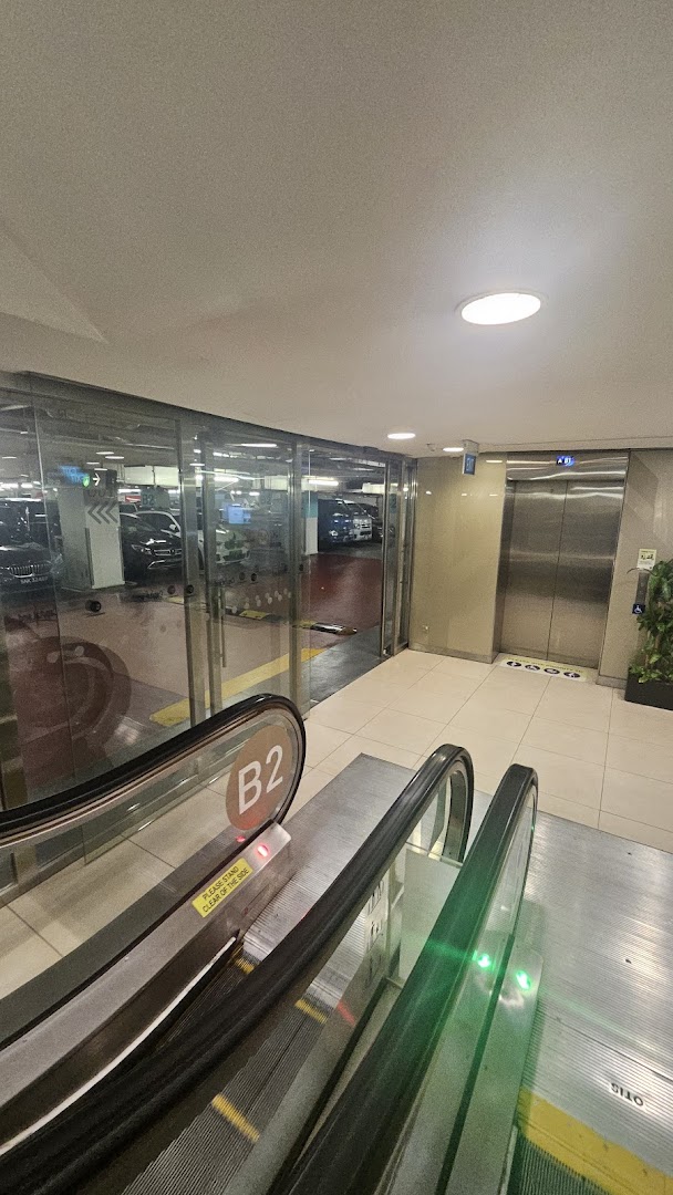 An escalator and elevator provide access to the B2 parking level of a shopping mall.