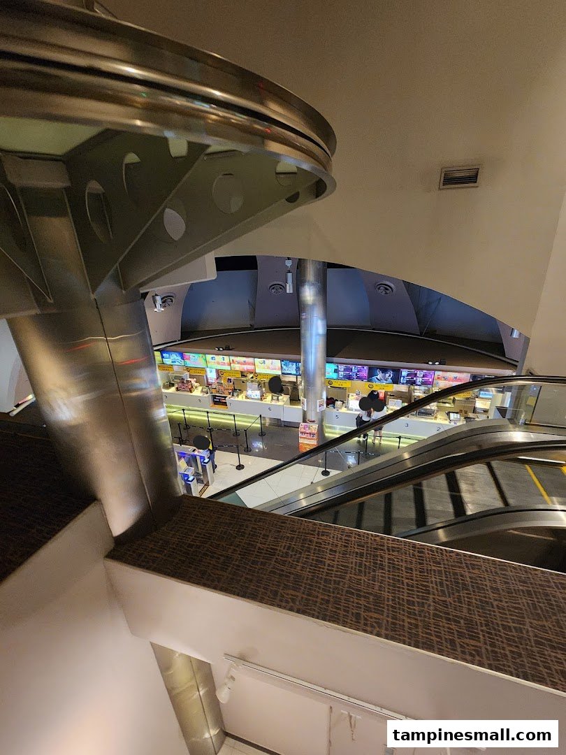An elevated view of Golden Village Tampines cinema lobby, featuring concession stands and escalators.