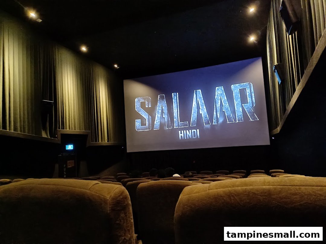 A cinema hall interior with plush seats and a large screen displaying 'SALAAR HINDI'.