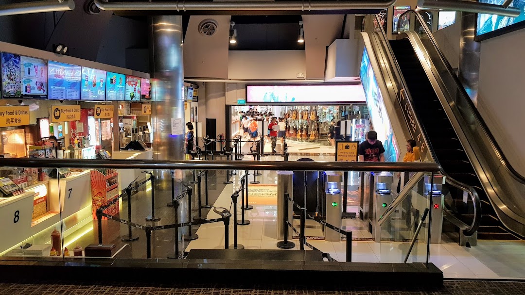 Interior view of Golden Village cinema lobby with concession stands, ticket gates, and escalator.