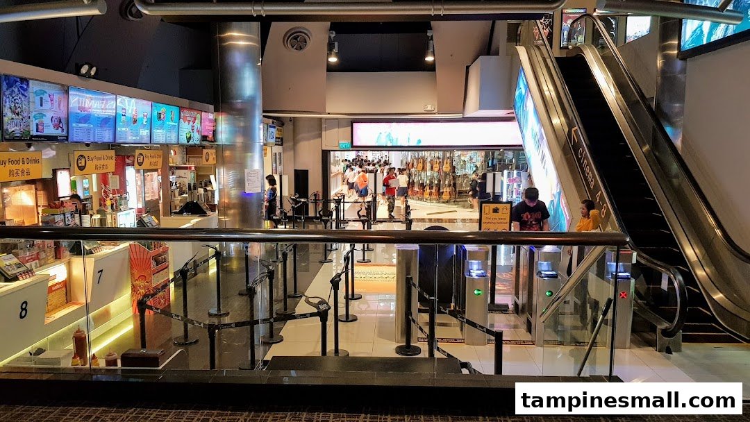Interior view of Golden Village cinema lobby with concession stands, ticket gates, and escalator.