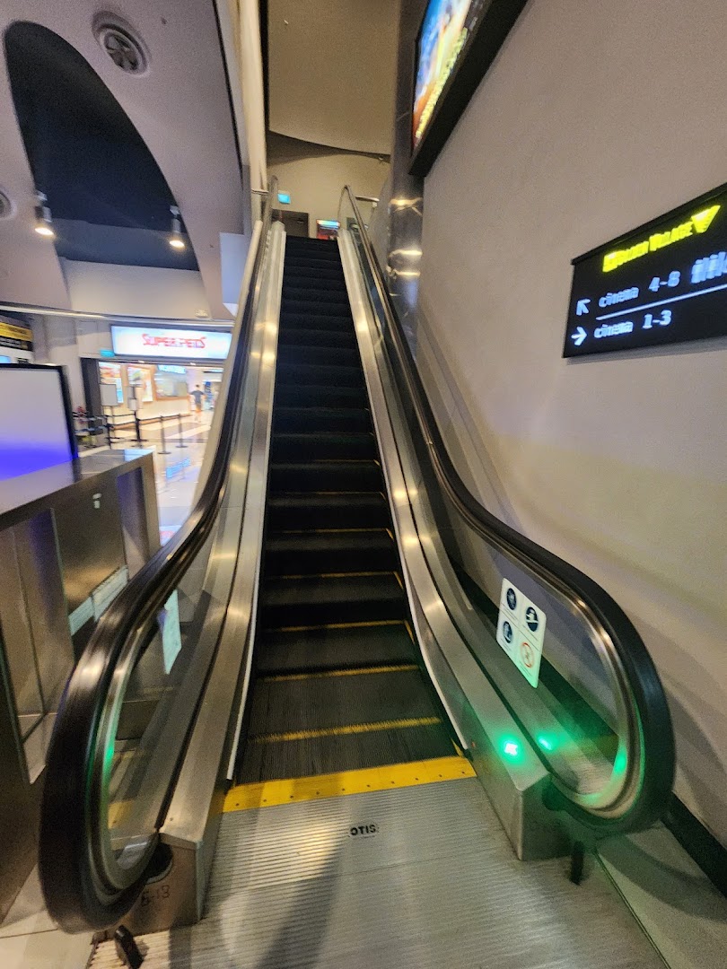 An escalator leading up to Golden Village Tampines cinema halls with directional signage.