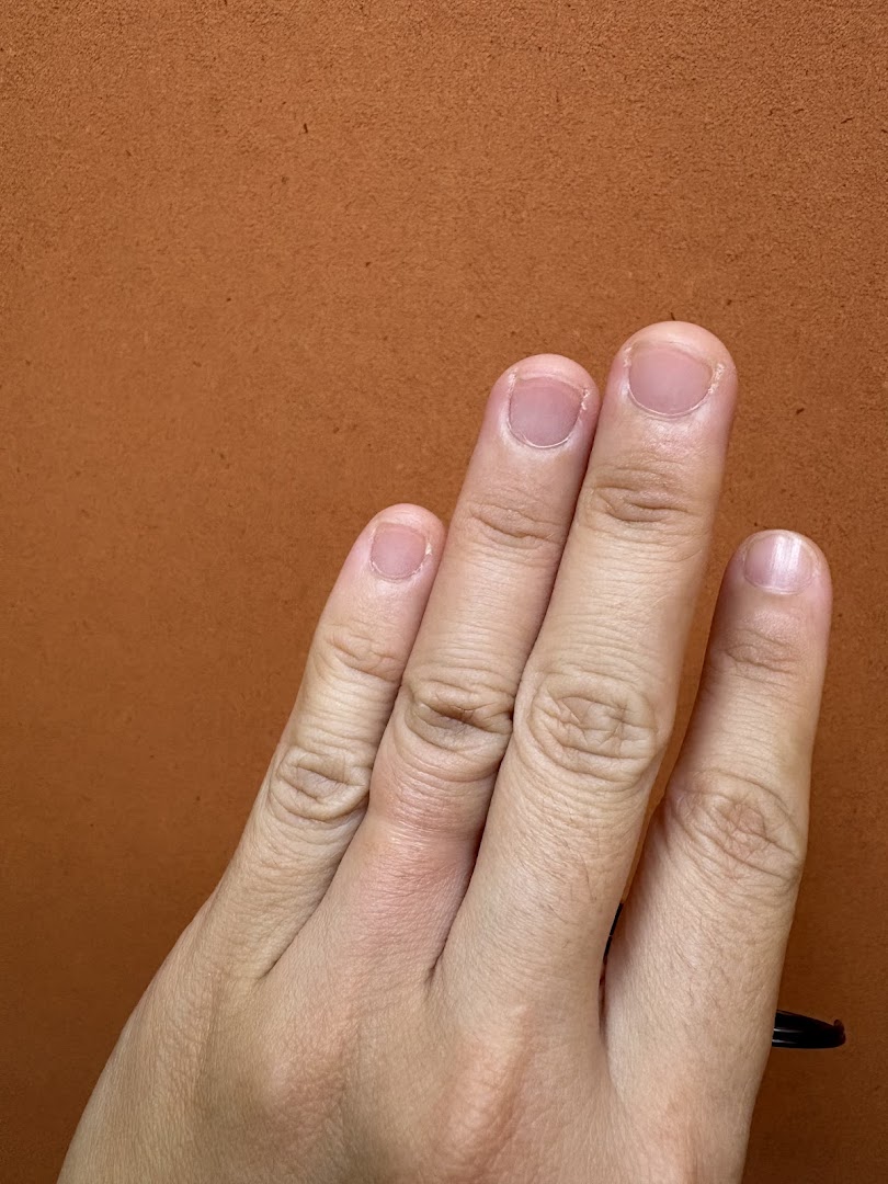 A close-up shot of a human hand with fingers extended against a textured orange background.