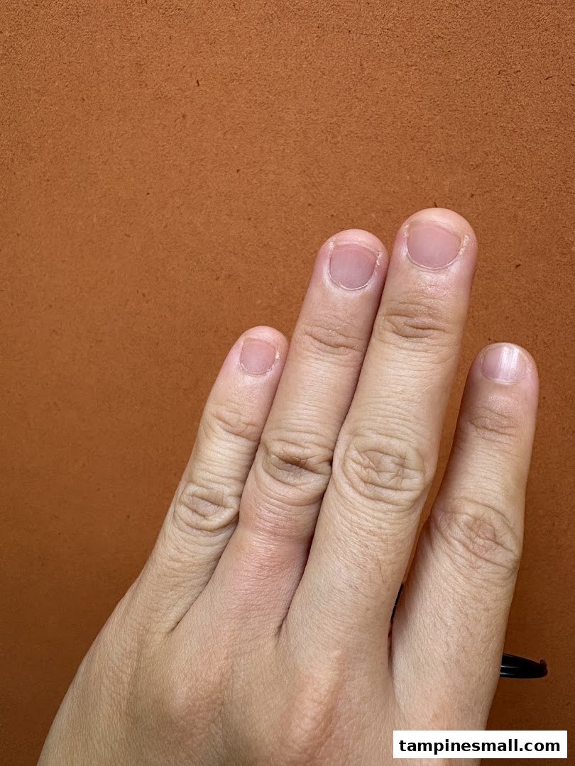 A close-up shot of a human hand with fingers extended against a textured orange background.