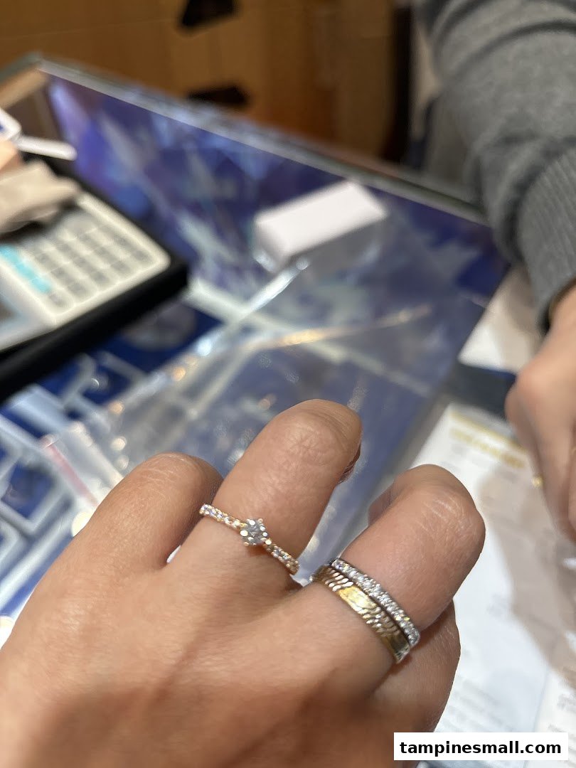 A hand models two elegant rings, a solitaire and a diamond band, at Goldheart Jewelry.