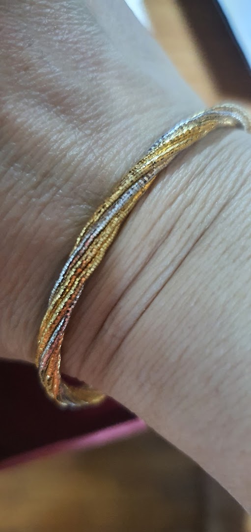Close-up of a multi-tone gold bracelet with intricate design worn on a wrist.