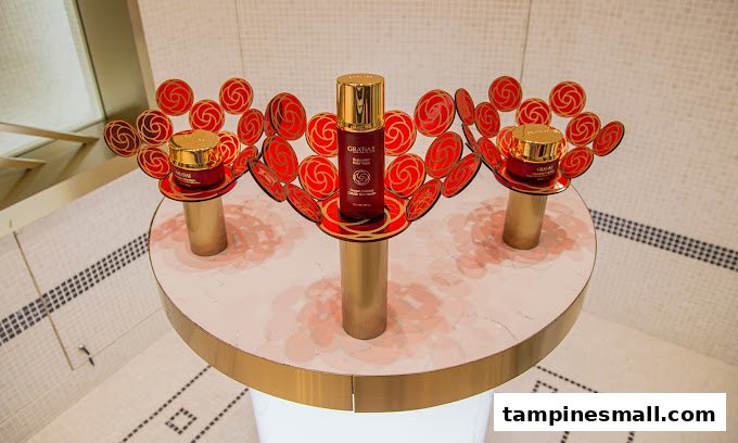 GRATiAE skincare products displayed on elegant stands with red and gold floral accents.