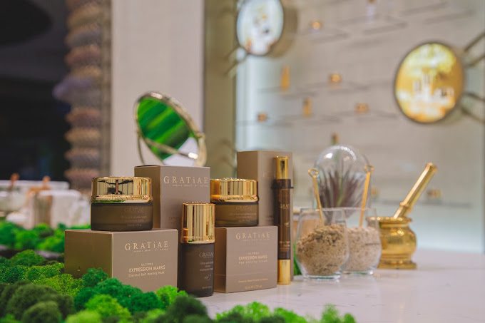 A display of GRATiAE skincare products, including creams and serums, on a moss-covered counter.