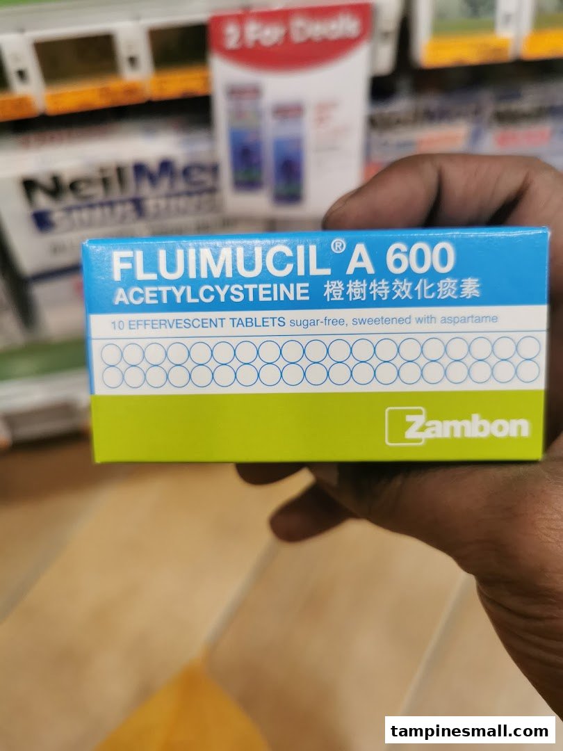 A hand holds a box of Fluimucil A 600 effervescent tablets inside a Guardian store.