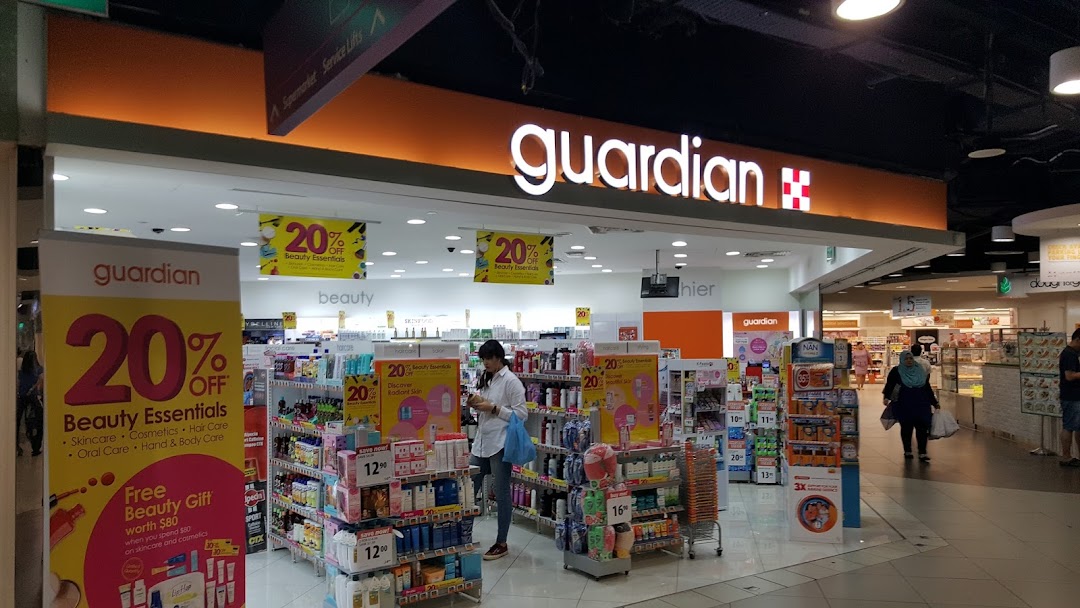 The entrance of Guardian Health & Beauty Pharmacy with promotional displays and customers inside.