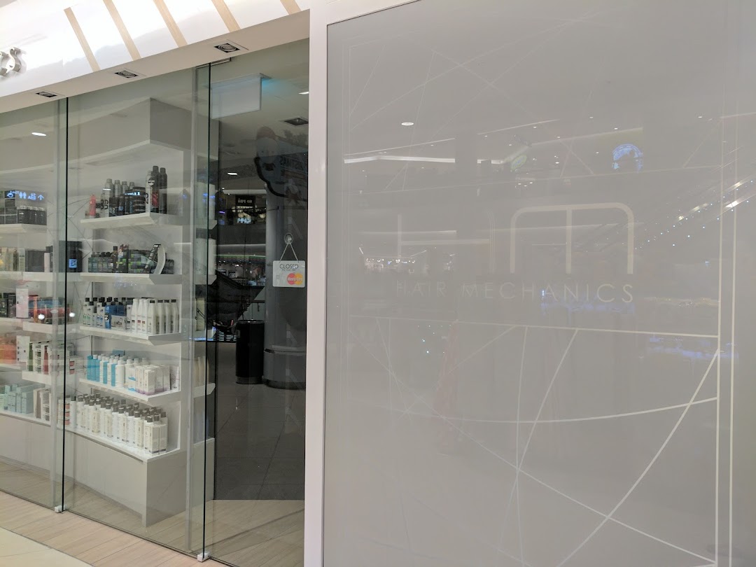 The glass storefront of Hair Mechanics, showcasing hair care products and the salon's entrance.