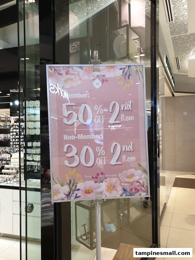 A promotional sign for Helen Tampines Mall offering 50% off for members and 30% off for non-members on the second item.