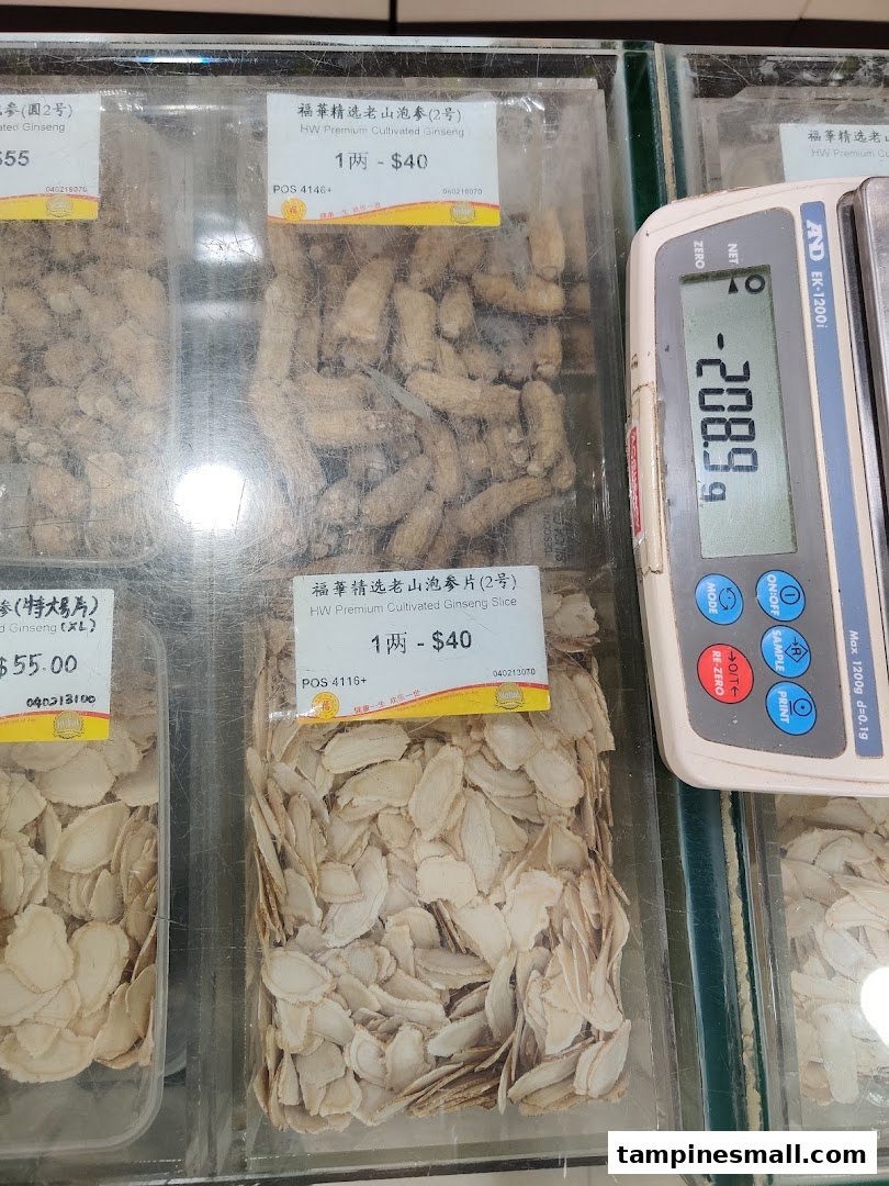 Close-up view of premium cultivated ginseng roots and slices displayed in clear containers with price labels and a weighing scale.