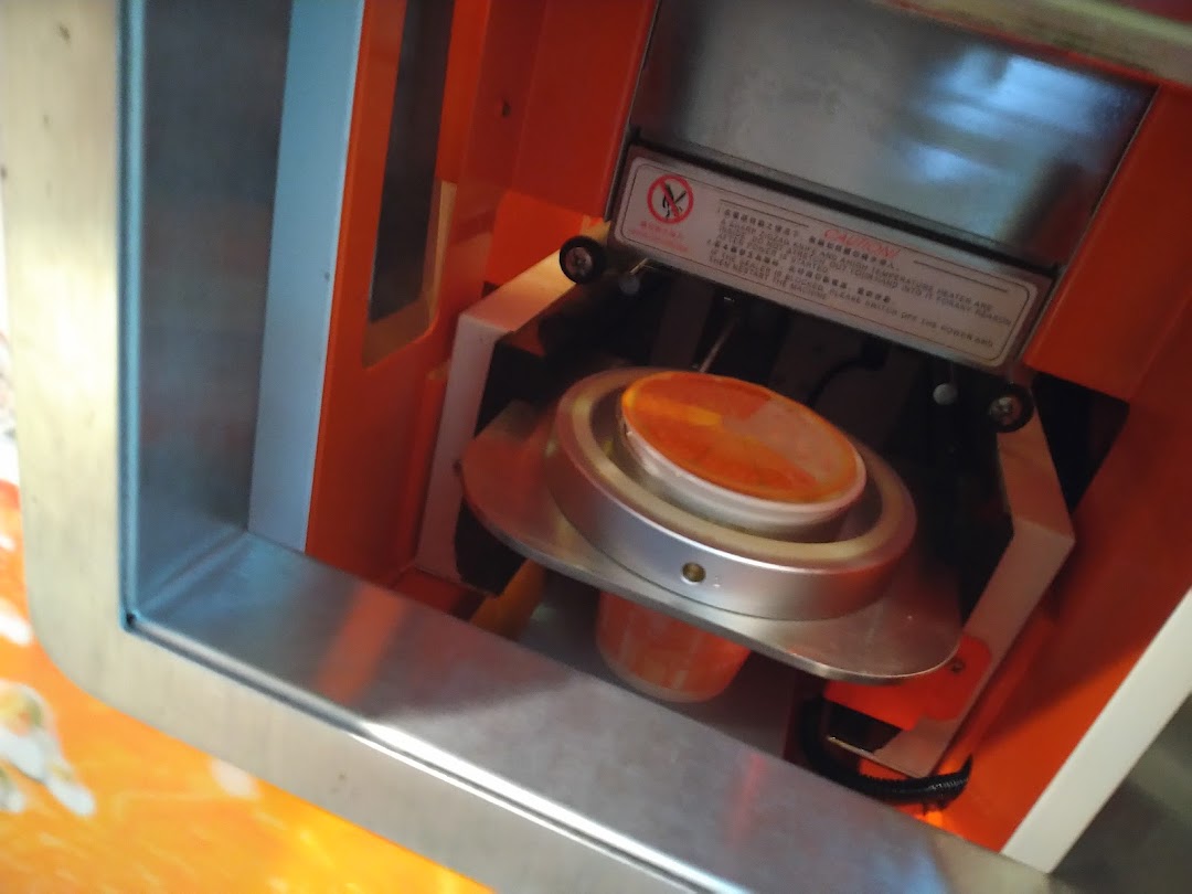 A close-up of a juice cup being sealed by an automated machine at iJooz.