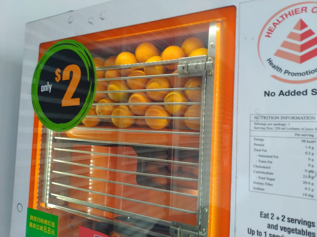 A close-up of an iJooz fresh orange juice vending machine displaying oranges and a $2 price.