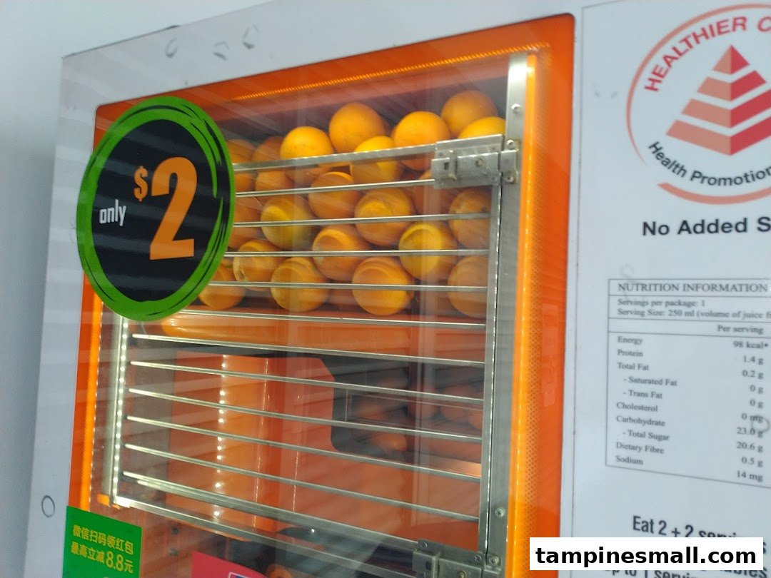 A close-up of an iJooz fresh orange juice vending machine displaying oranges and a $2 price.