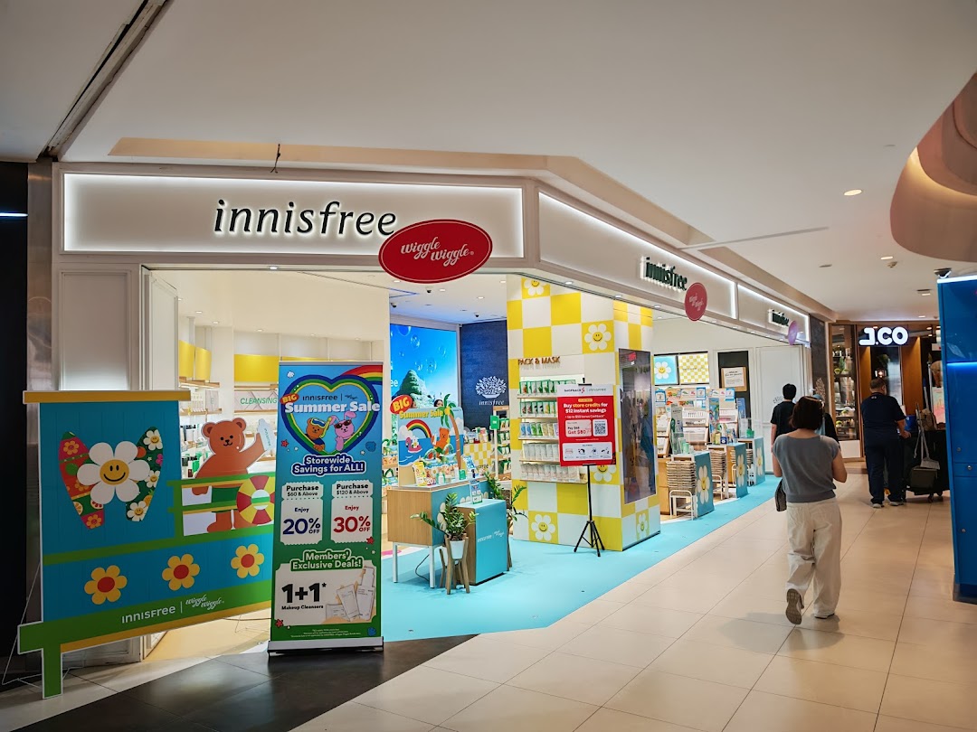 The vibrant Innisfree shop entrance features colorful displays, promotional banners, and a customer walking past.