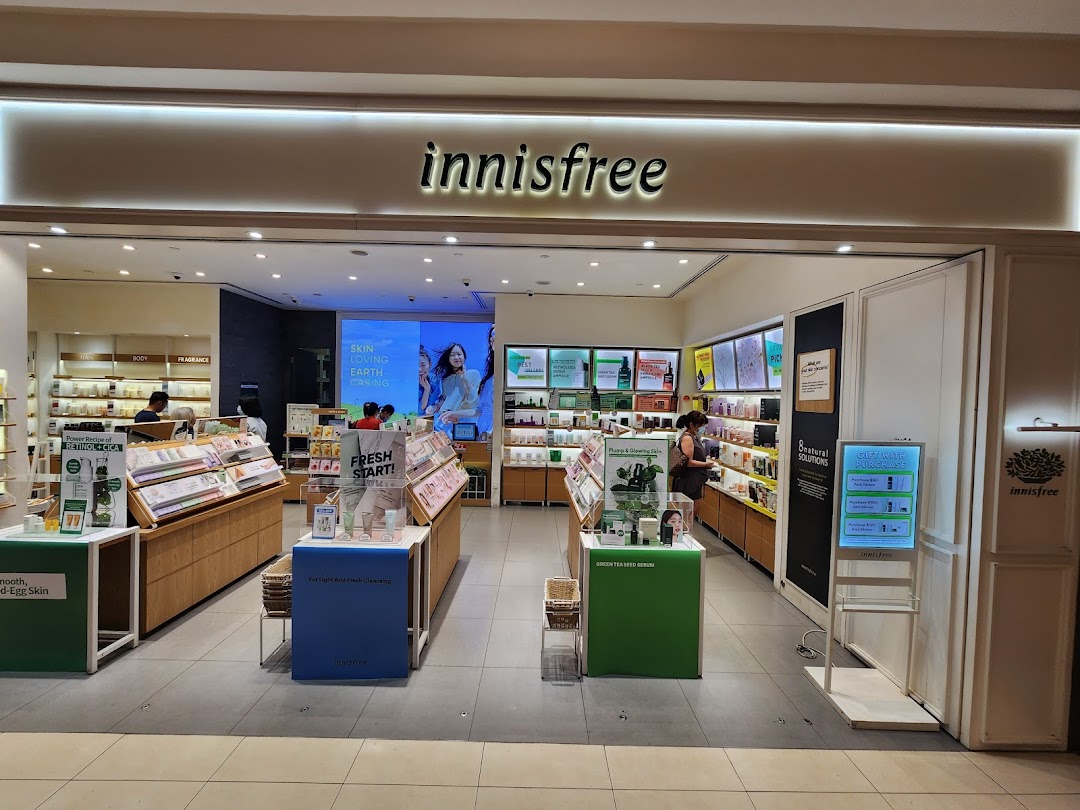 The image shows the brightly lit entrance of the Innisfree beauty store with product displays and customers inside.